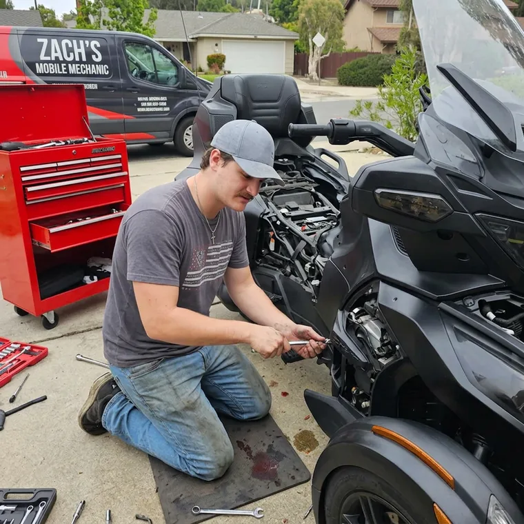 A mobile technician kneeling at a vehicle with a rolling toolbox and a service van behind