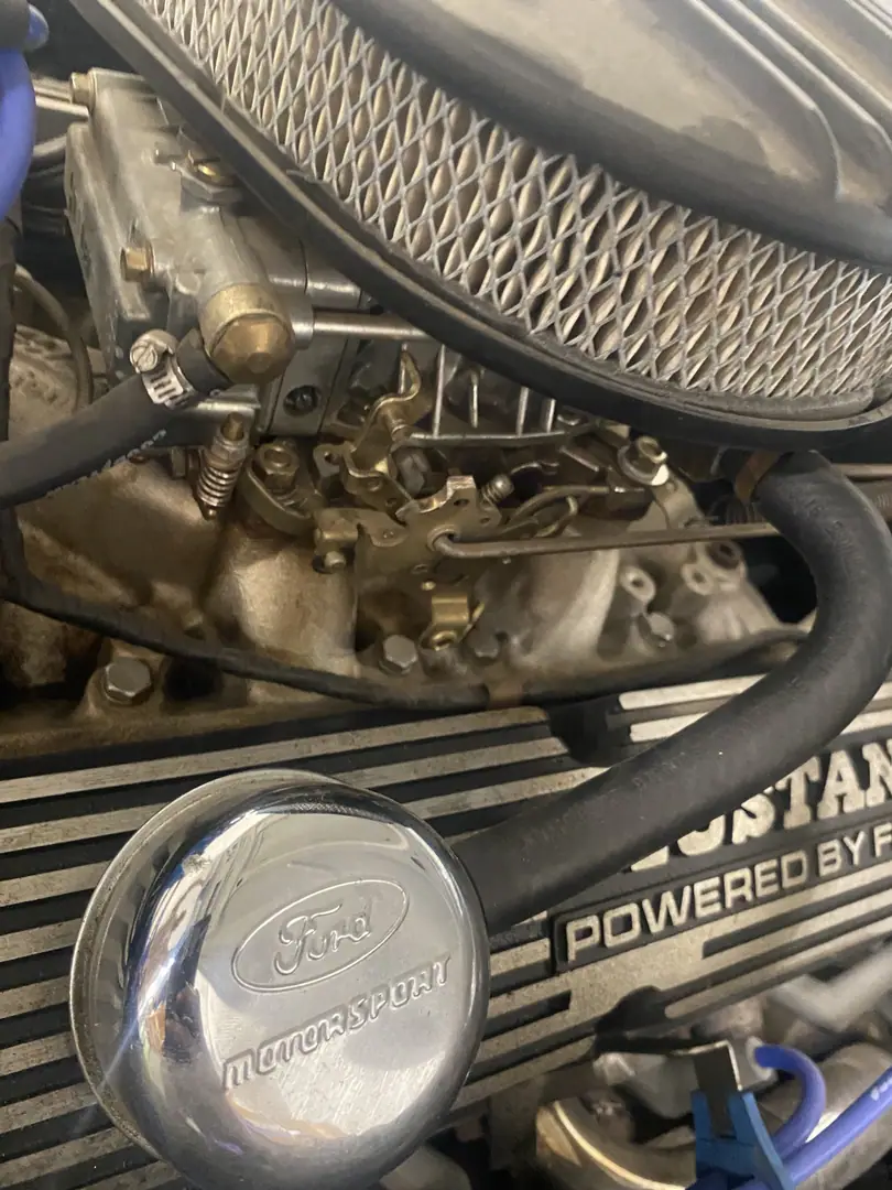 A Ford V8 with a chrome air cleaner and Powered by Ford valve cover in a classic Mustang