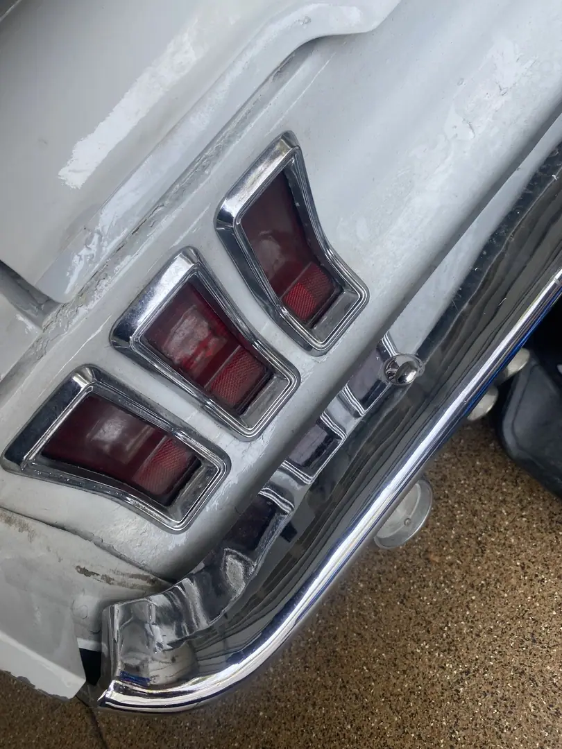 Close-up of the taillights and chrome rear bumper on a white classic Mustang