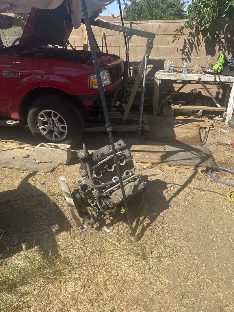 The removed Ranger engine sitting on the dirt next to the truck and the hoist