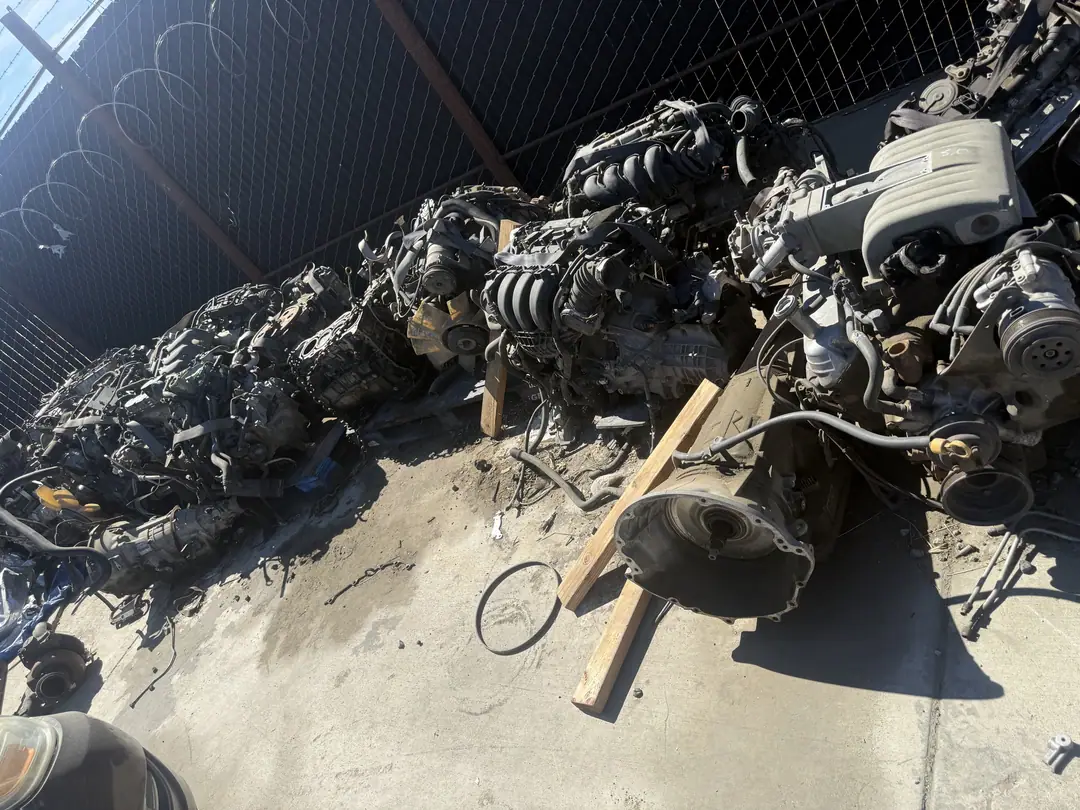 Several used engines lined up on pallets on the gravel at a salvage yard