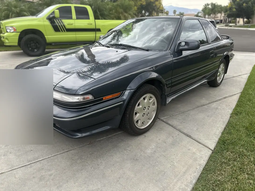 A gray Toyota coupe parked at the curb on a sunny street