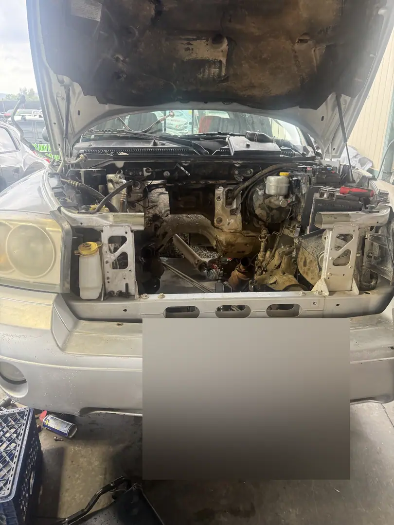 A GM truck with the hood up and the engine removed, the empty engine bay showing the frame