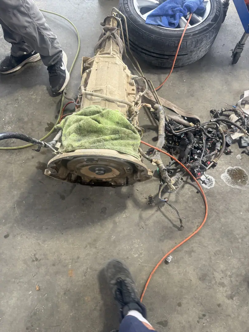 An automatic transmission on the ground after removal with wiring beside it