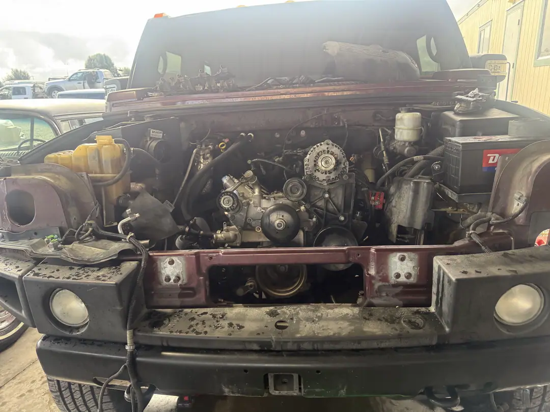 The front of a Hummer H2 with the grille and front end opened up and the V8 exposed