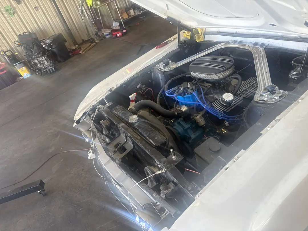 The classic Mustang in the shop bay in December 2025 with the hood open