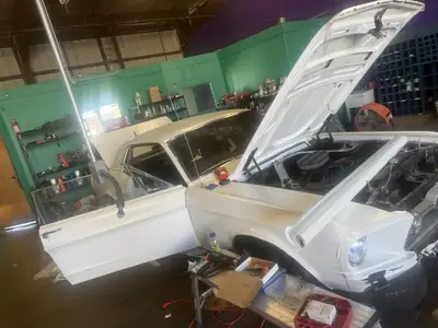 Mustang in the bay with the hood up during engine install