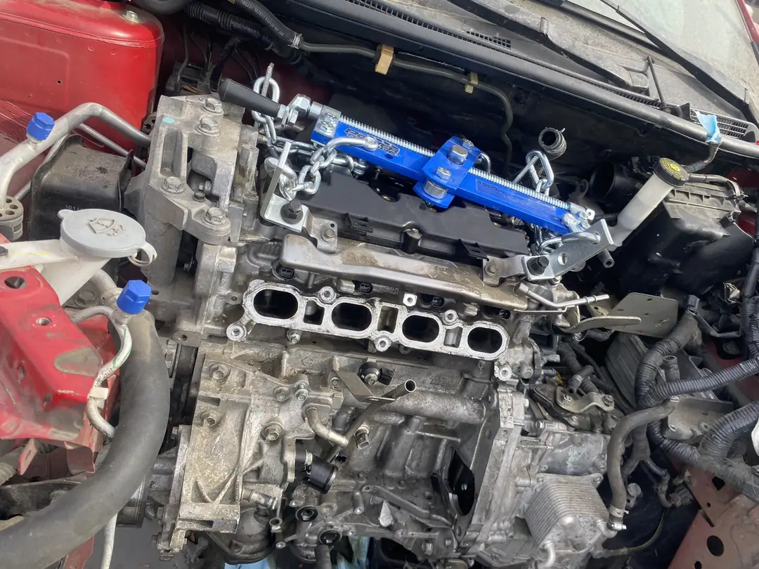 A Nissan engine with the intake off and a blue lift bracket bolted on, ready to come out