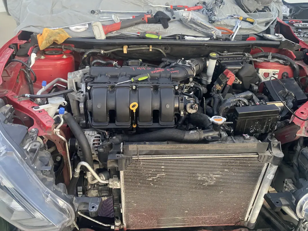 The red Nissan engine bay with the new engine, intake and radiator back in place