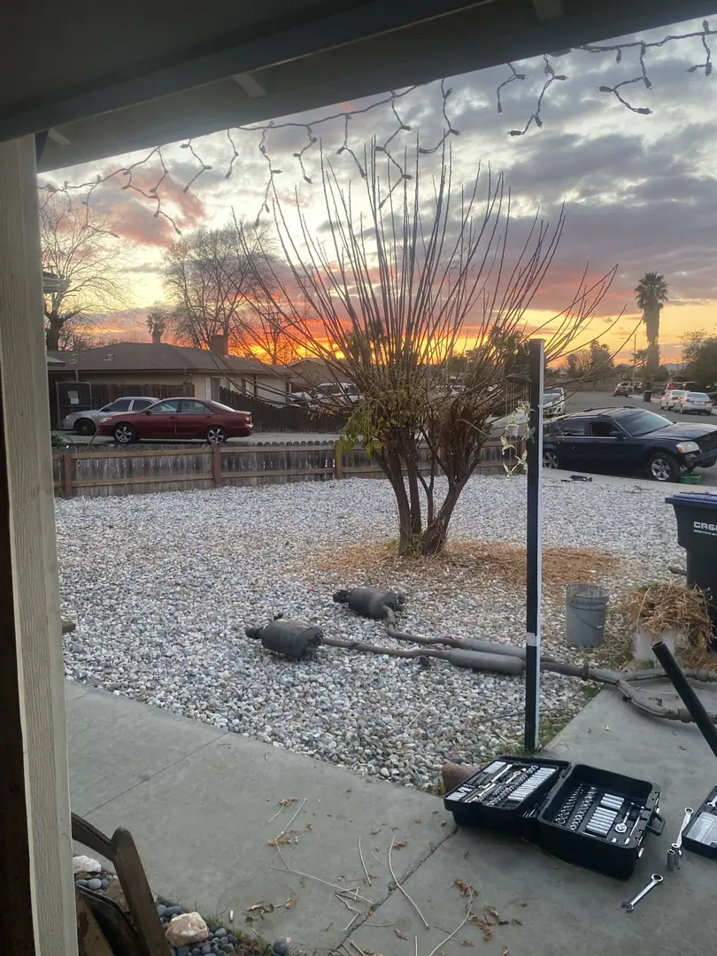 A sunset over the gravel yard and driveway with a jack stand and toolbox in the foreground