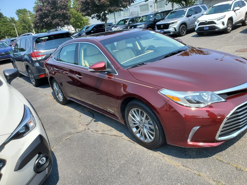 A red Toyota Avalon Hybrid on a dealer lot during a Supercanic pre-purchase inspection
