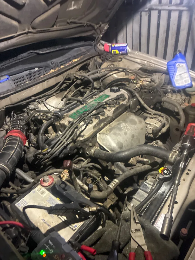 Engine bay of a 1998 Honda Accord EX at night with a jump pack connected to the battery