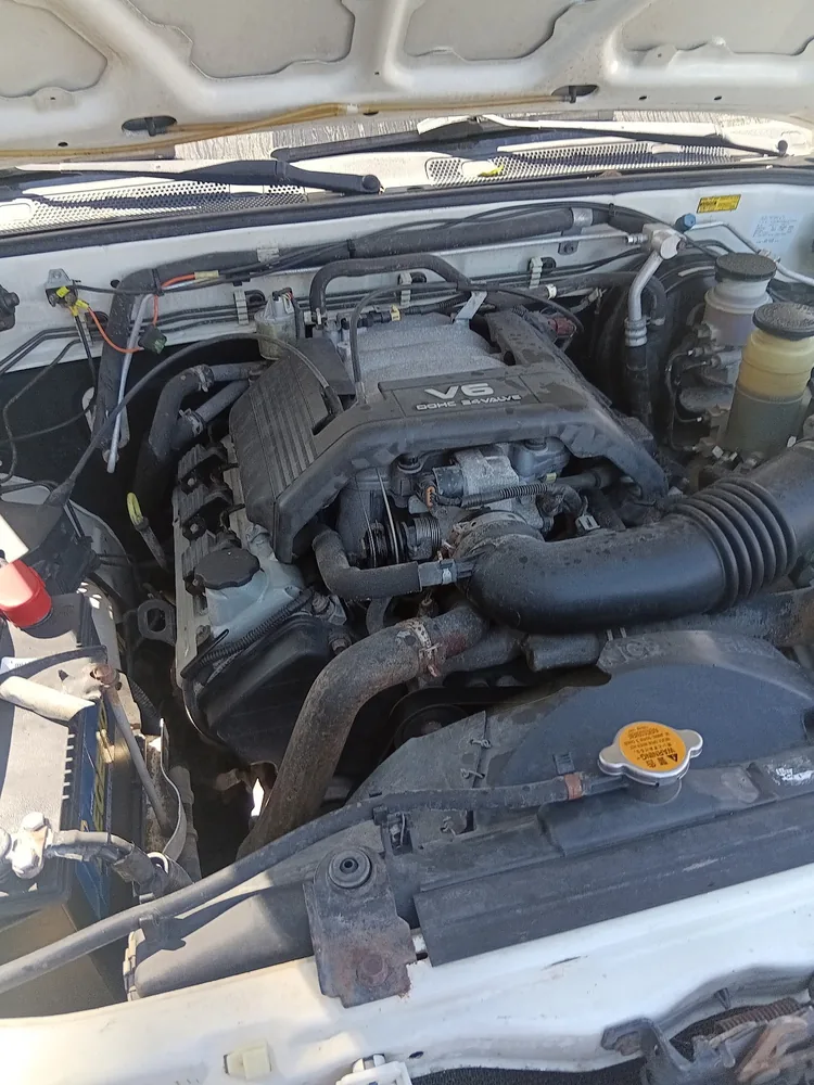 The V6 engine bay of a white 1998 Isuzu Rodeo with the hood up