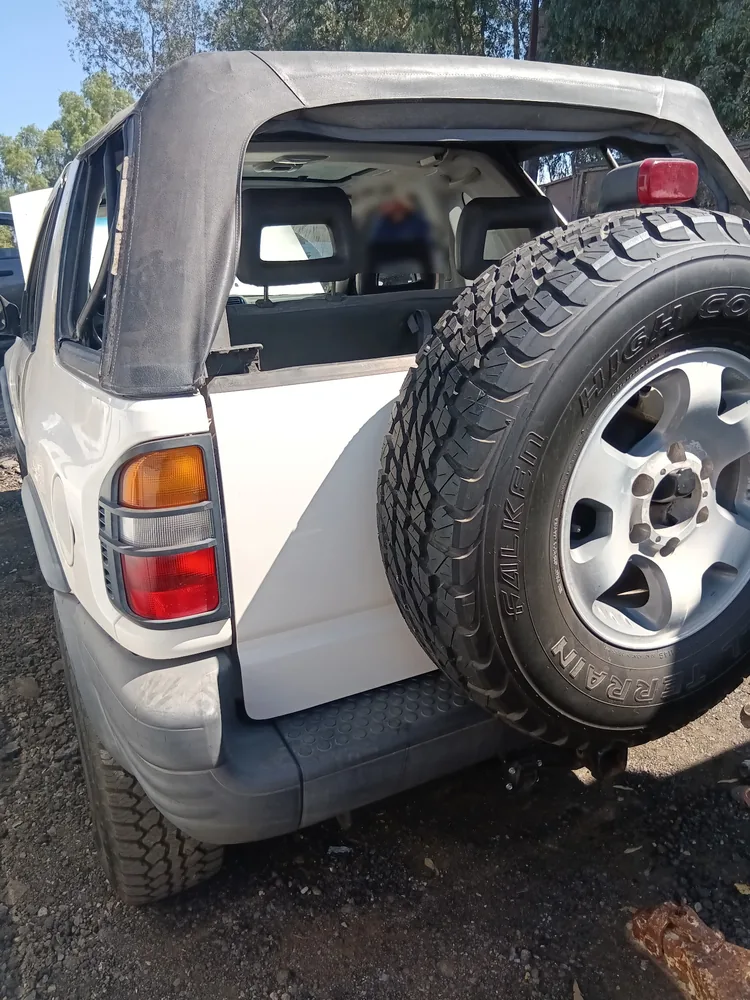 The rear of a white 1998 Isuzu Rodeo with a spare tire on the back gate