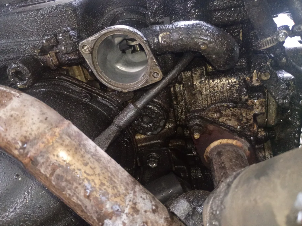 Thermostat housing on a 1998 Subaru Impreza engine with the hose removed and grime around it