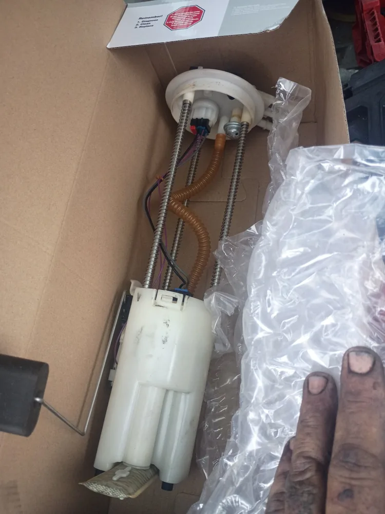 A new fuel pump module for a 1999 Silverado in its box, held by a mechanic's hand