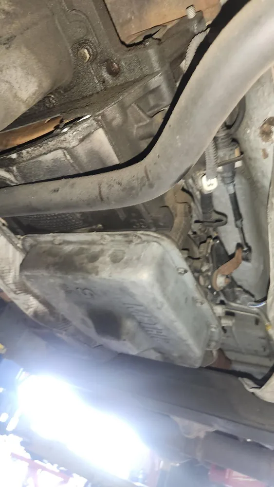 Underside of a 2004 Ford F150 on a lift showing the transmission pan and exhaust pipe