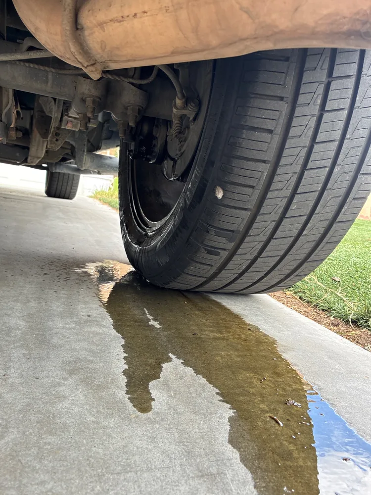 Brake fluid pooled on a driveway under the passenger side wheel of a 2004 Chevy Silverado