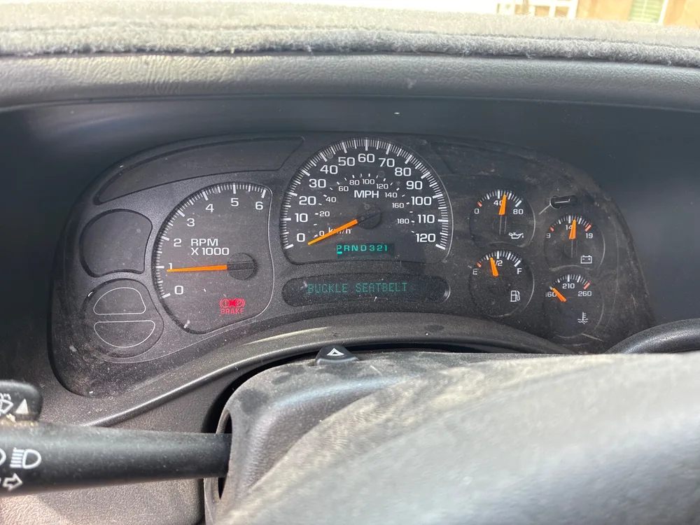 The dash of a 2004 Chevy Silverado with the red brake warning light on