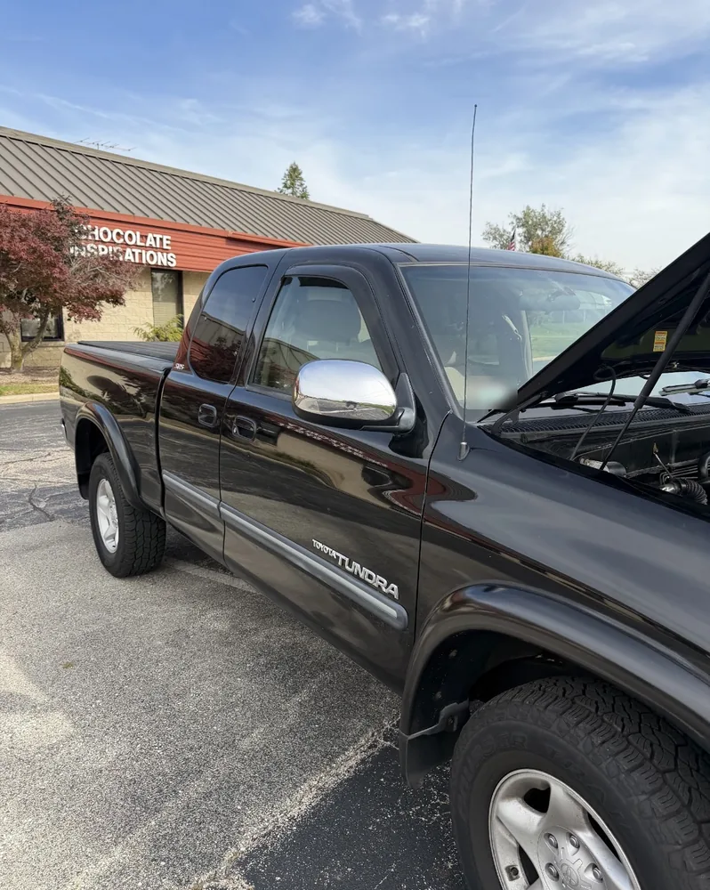 A black 2004 Toyota Tundra SR5 extended cab with the hood open in a parking lot