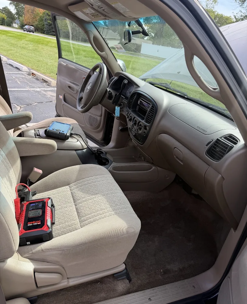 Inside the 2004 Toyota Tundra cab with a scan tool plugged in and a jump pack on the floor