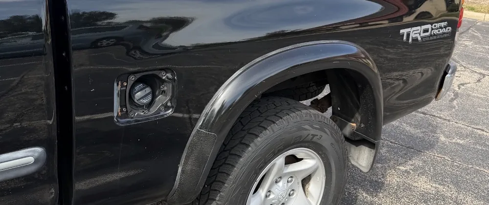 Side of the black 2004 Tundra bed with the fuel door open and the TRD Off Road decal