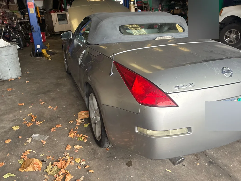 A silver 2005 Nissan 350Z roadster with its soft top up, parked in the Supercanic shop