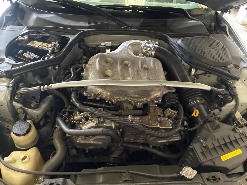 The engine bay of the 2005 Nissan 350Z with the hood open in the Supercanic shop