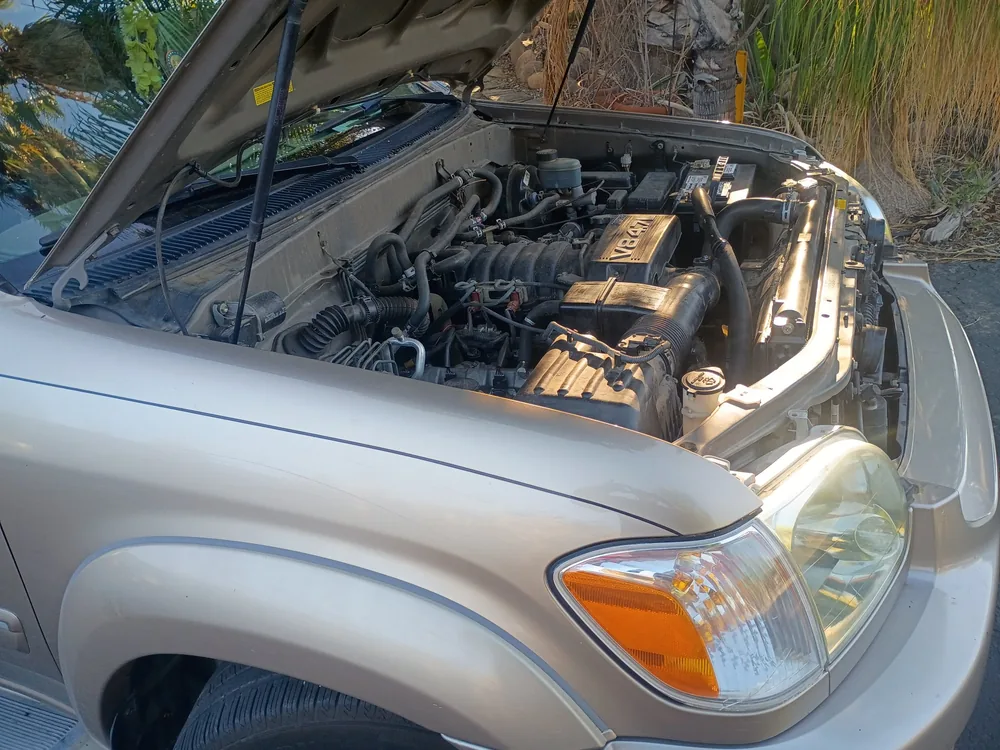 A gold 2007 Toyota Sequoia with the hood up and its 4.7 liter V8 showing, parked in a driveway