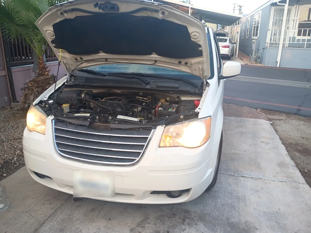 A white 2010 Chrysler Town and Country minivan with the hood up at the owner's home in Hemet