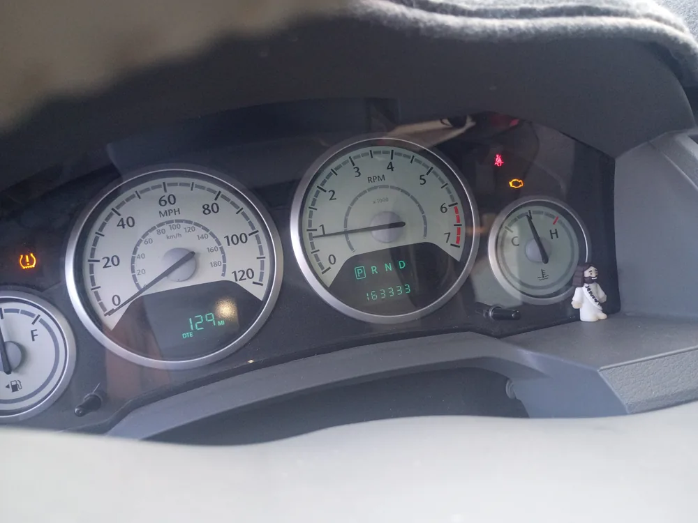 Instrument cluster of a 2010 Chrysler Town and Country showing 163,333 miles and the check engine light