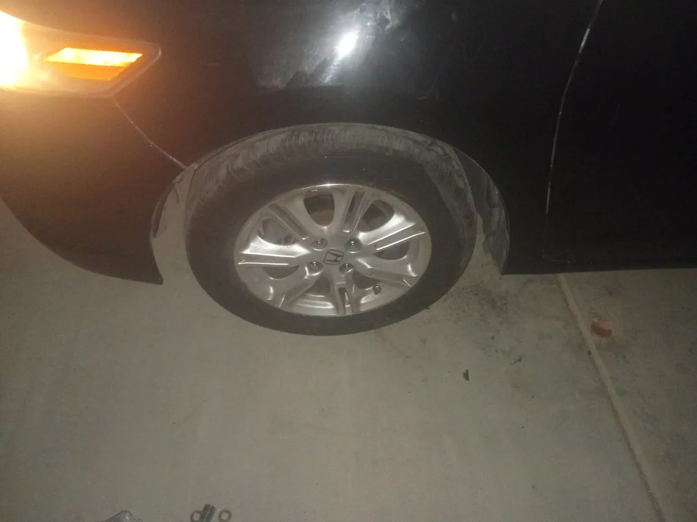 Front wheel of the black 2010 Honda Insight back on the car at night