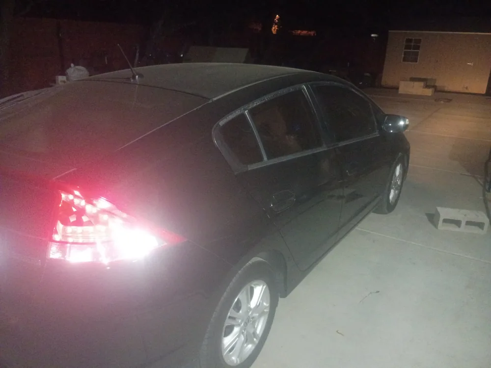 The black 2010 Honda Insight in a driveway at night after the repair