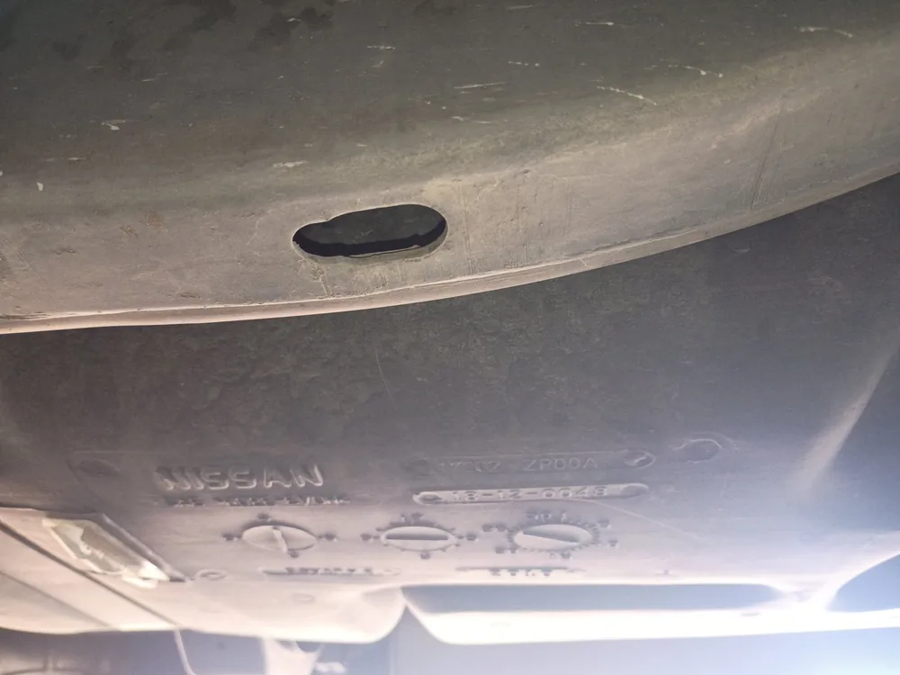 Underside of a 2010 Nissan Frontier showing the fuel tank and its stamped markings