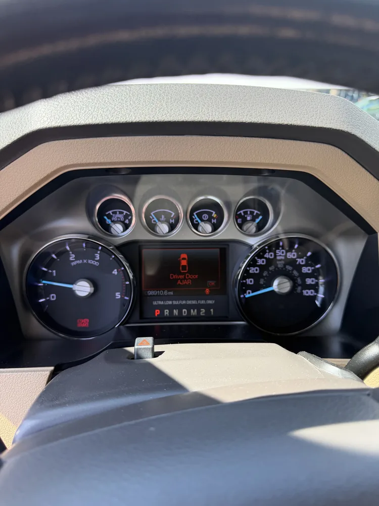The instrument cluster of a 2011 Ford F-250 diesel showing the odometer and a door ajar message