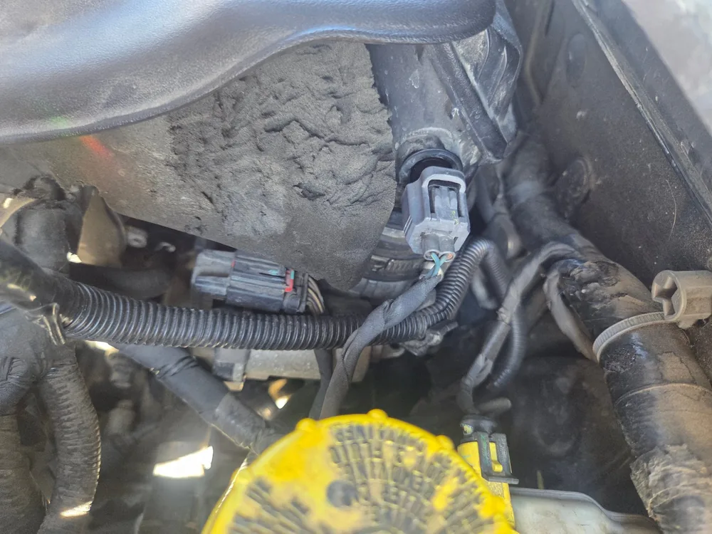 The intake air temperature sensor connector plugged into the intake tube under the hood of a 2013 Dodge Dart
