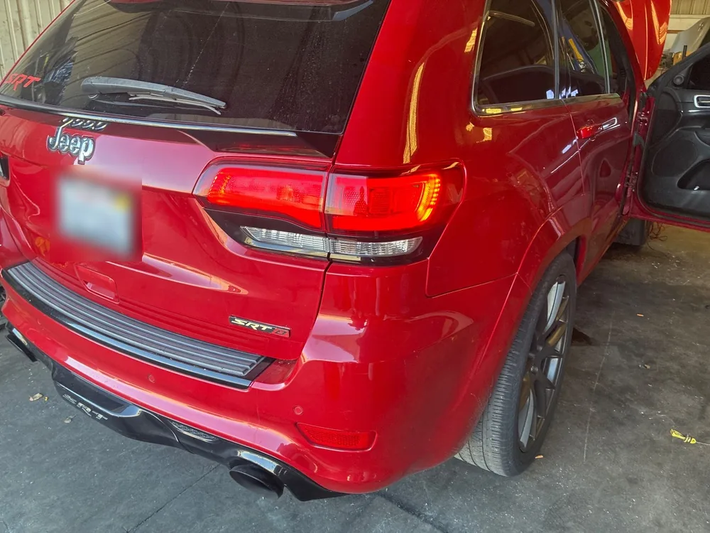 Rear of a red 2015 Jeep Grand Cherokee SRT parked in a garage with the driver door open