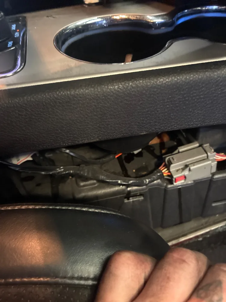 Wiring and a gray connector under the center console of a 2015 Jeep Grand Cherokee SRT, with the trim pulled back