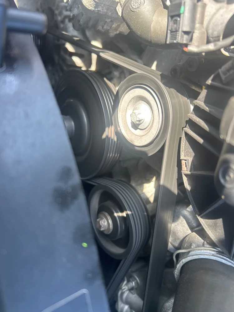 The serpentine belt and pulleys on the front of the engine in a 2015 Mercedes G550