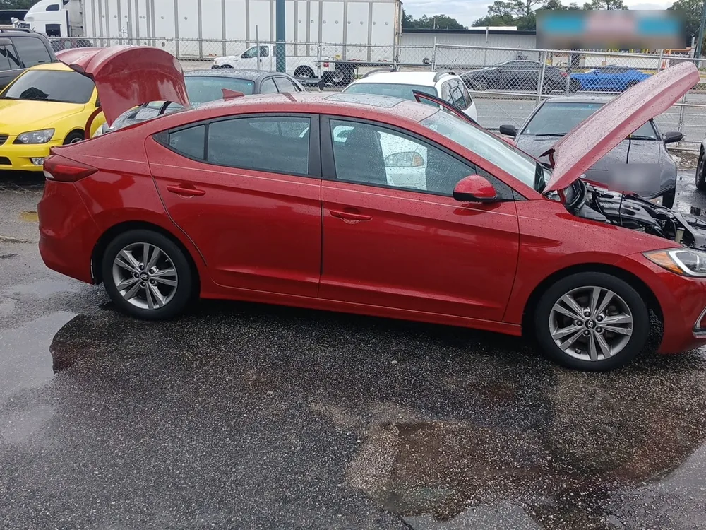 A red 2017 Hyundai Elantra with the hood and trunk open on a wet lot in Orlando