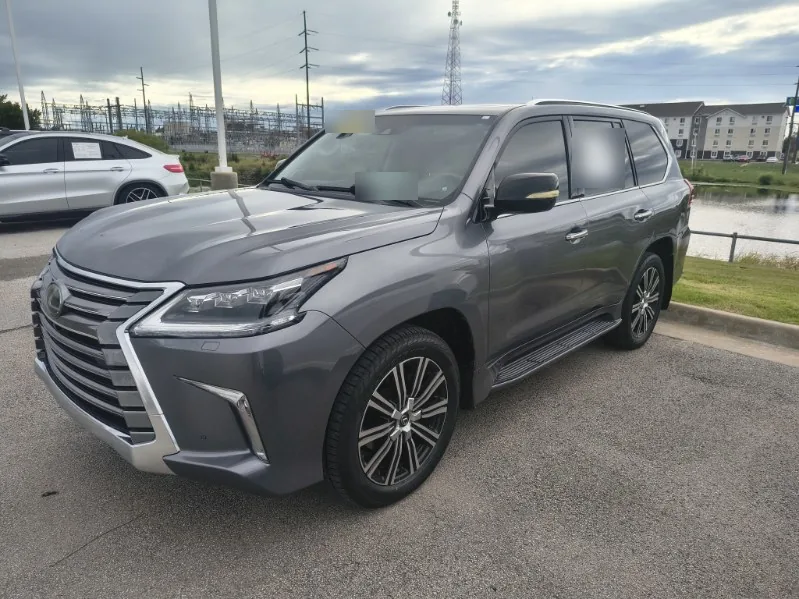 A gray 2018 Lexus LX570 parked on a dealer lot in Tulsa under a cloudy sky