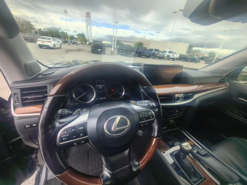 The driver seat view of a 2018 Lexus LX570 showing the wood and leather steering wheel and dash