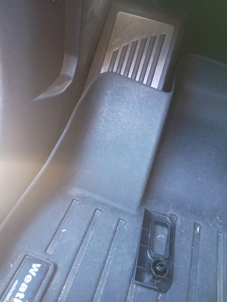 The driver footwell of the 2020 Alfa Romeo Stelvio where the hood release lever mounts, with the lever housing exposed
