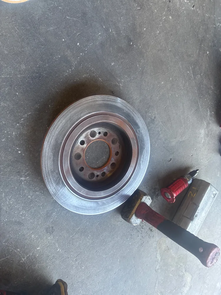 A brake rotor off the Tucson lying on the shop floor next to a tool