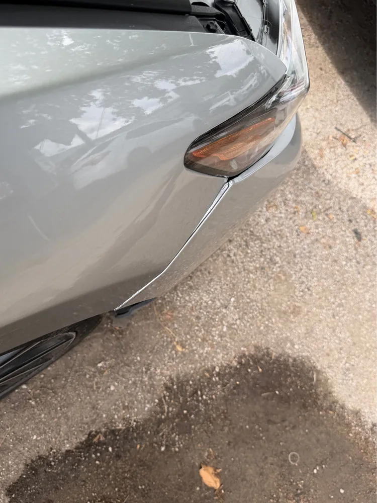 The front corner of a silver 2022 Toyota Camry SE with a gap between the bumper and the fender below the headlight