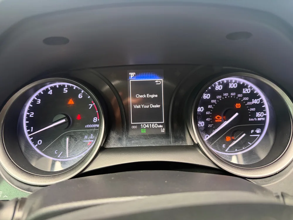 The gauge cluster of a 2022 Toyota Camry SE with the check engine light on, a Check Engine Visit Your Dealer message and 104,160 miles