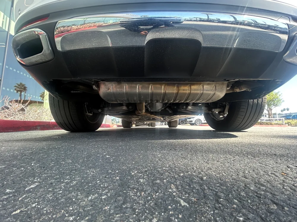 A low view under the rear of a 2025 Mercedes GLE showing the exhaust, rear suspension and both rear tires