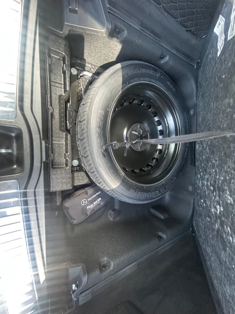 The spare tire well of a 2025 Mercedes GLE with the space saver spare and first aid kit in place