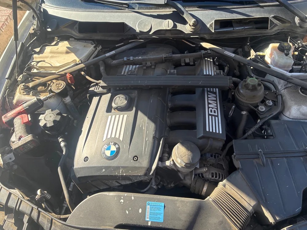 Top view of the BMW 128i engine bay with the six cylinder engine cover, intake and strut brace