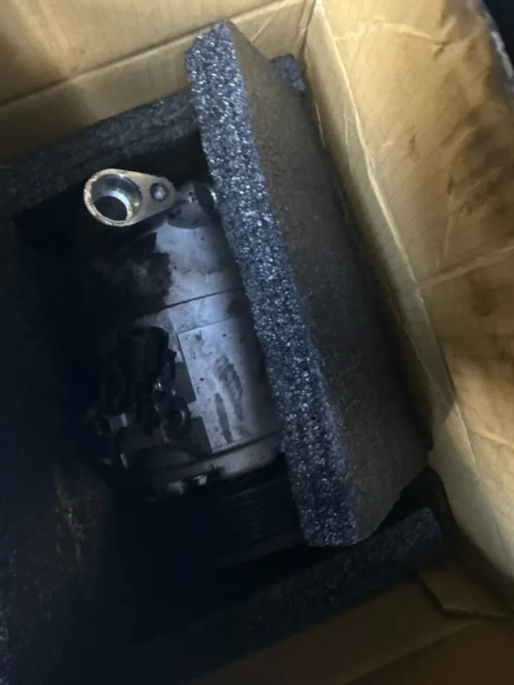 An A/C compressor packed in foam inside a cardboard box
